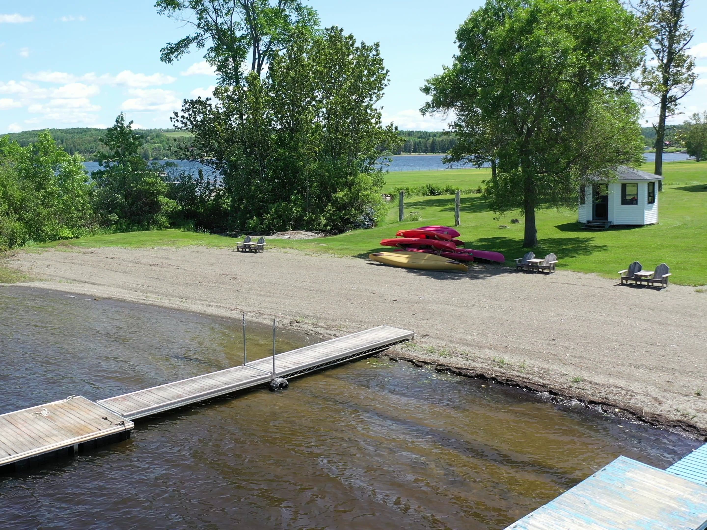 The beach and dock from above, with kayaks pulled up on the sand and the lake behind.